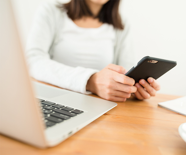 woman using cell and computer